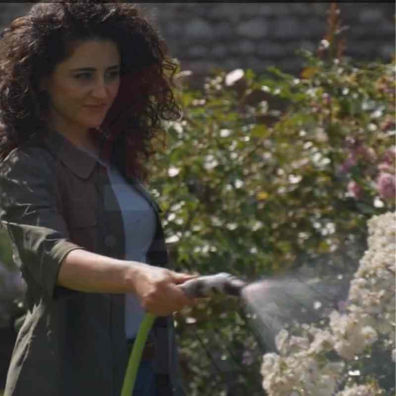 Mujer usando la manguera Fitt Nts Force para regar su jardín