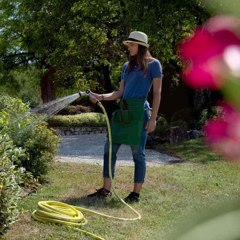 Mujer usando la manguera Fitt Nts Tobby para regar su jardín